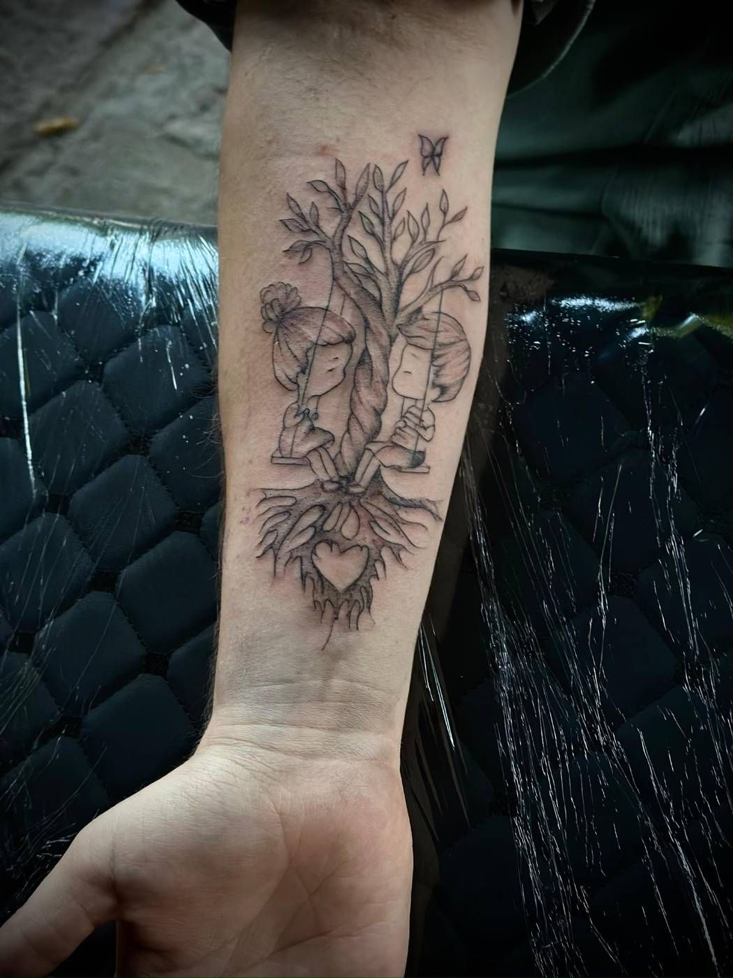Tattoo mit Baum und Schaukeln am Unterarm